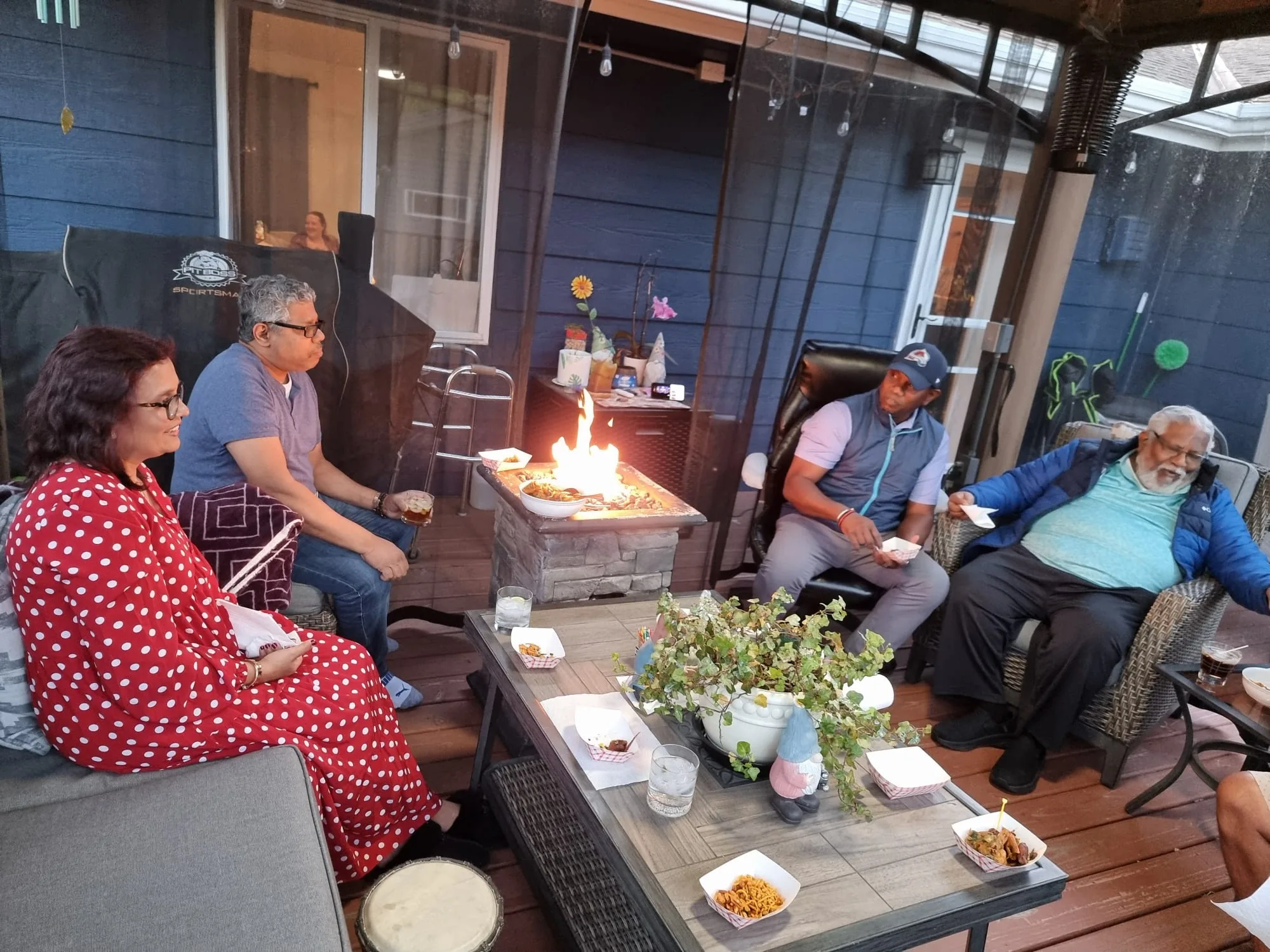 Family relaxing with food and drinks around the fire on Ravi and Jo's patio